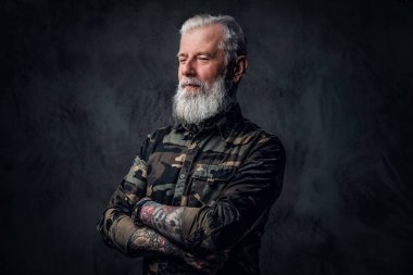 Kamuflaj kıyafeti giymiş, dövmeli, modaya uygun yaşlı bir adam.