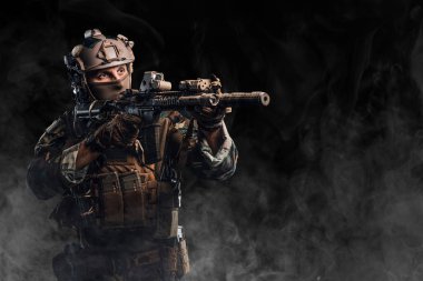 Kamuflaj üniformalı özel kuvvetler askeri lazer görüşlü bir saldırı tüfeği tutuyor.