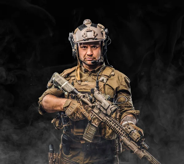 Боевой солдат с серьезным лицом держит винтовку на черном фоне — стоковое фото