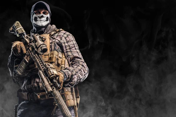 Bekämpande soldat med mask håller gevär mot svart bakgrund — Stockfoto