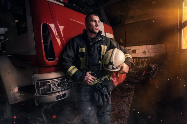 Orgulloso bombero posando alrededor de camión de bomberos dentro de la estación de bomberos — Foto de Stock