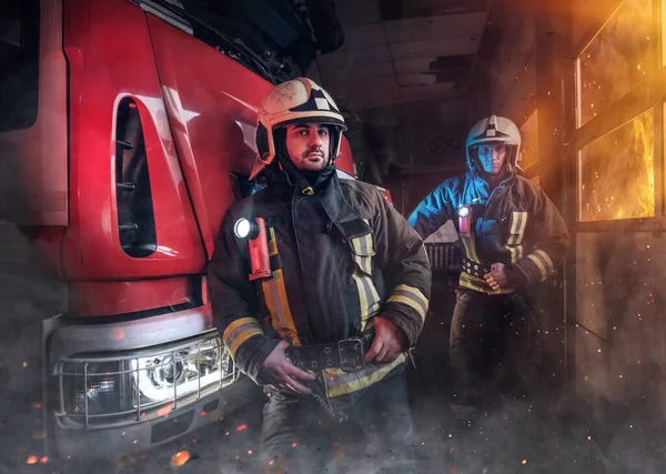 Profesionální tým dvou hasičů kolem hasičského vozu v hasičské stanici — Stock fotografie