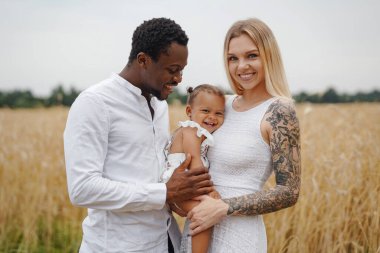 Çok ırklı genç bir aile gündüz vakti doğada birlikte dinleniyor.