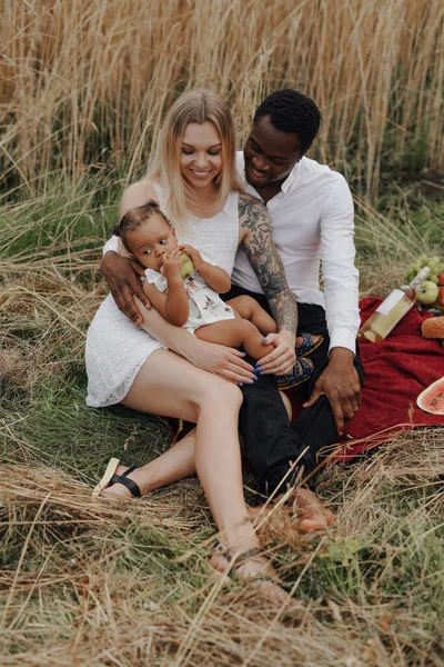 Neşeli melez bir aile gündüz piknik yapıyor.