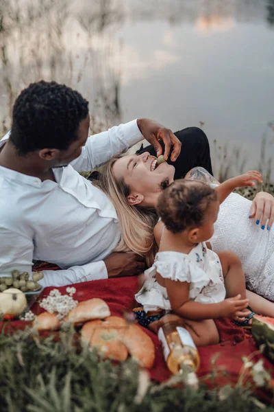 Liten flicka som har picknick med sin far och mor utomhus — Stockfoto