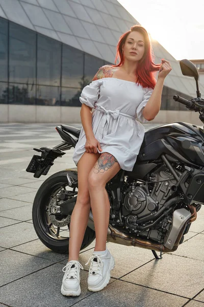 Татуированная женщина-байкер и черный мотоцикл на открытом воздухе в городе — стоковое фото
