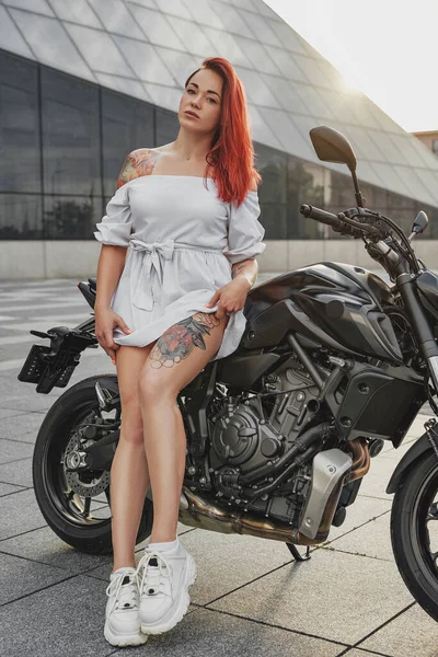 Mulher legal motociclista com motocicleta preta ao ar livre em dia ensolarado — Fotografia de Stock