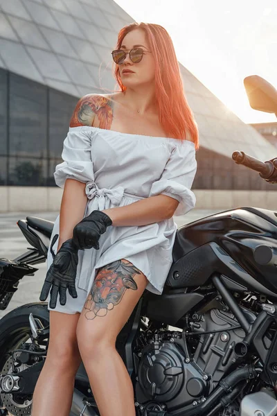 Модная женщина-мотоциклист с мотоциклом на открытом воздухе в городе — стоковое фото