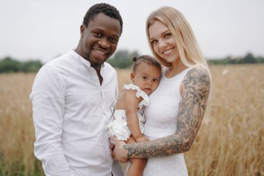 Çok ırklı genç bir aile gündüz vakti doğada birlikte dinleniyor.