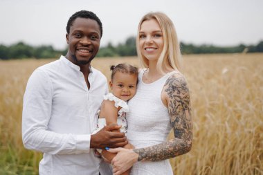 Çok ırklı genç bir aile gündüz vakti doğada birlikte dinleniyor.