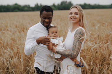 Bir çocuğu buğday tarlalarında tatilde olan çok kültürlü bir aile.