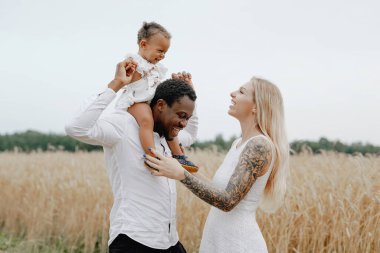 Baba buğday tarlalarında çocuğunu sırtında taşıyor.