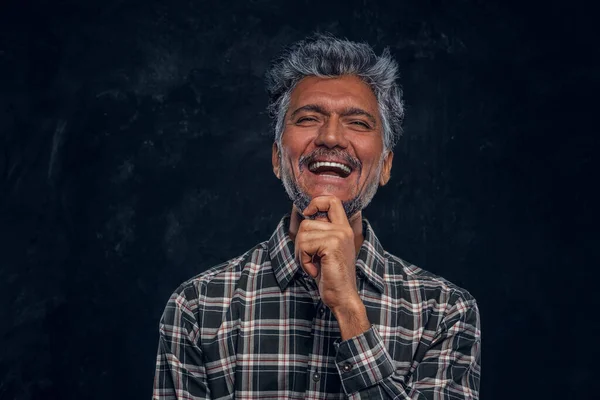 Homem idoso feliz vestido com camisa xadrez contra fundo escuro — Fotografia de Stock