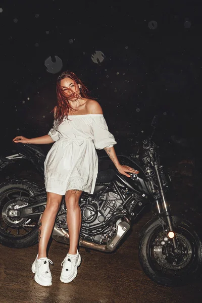 赤頭女性とともに黒バイク屋外で夜 — ストック写真