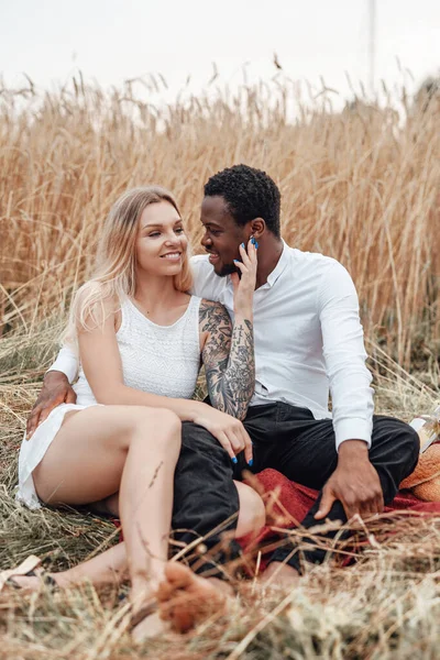 Çok ırklı bir çift buğday tarlalarında birlikte dinleniyor.