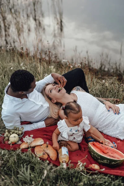 Küçük kız anne ve babasıyla dışarıda piknik yapıyor.