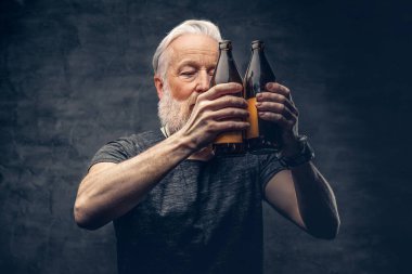 Uzun sakallı büyükbaba elinde iki şişe siyah arka plan tutuyor.