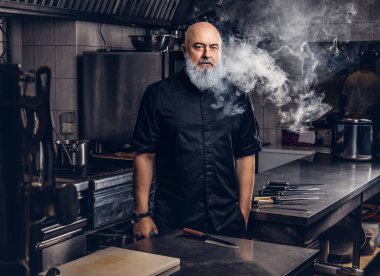 Restoranın mutfağında sigara içen profesyonel yaşlı fırıncı.