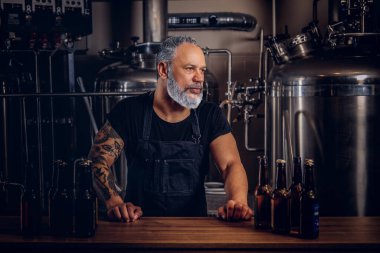 Bira fabrikasında bira şişeleriyle poz veren yaşlı adam.