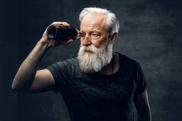 Modern saç stili olan yaşlı adam şişeden bakıyor. — Stok fotoğraf