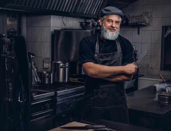 Chef viejo fresco del hombre que sostiene el cuchillo en cocina moderna — Foto de Stock