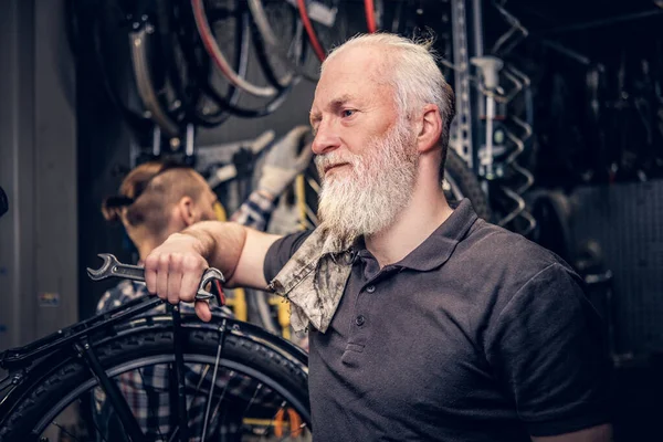 Reparador profesional de bicicletas que trabaja en un taller de reparación moderno — Foto de Stock