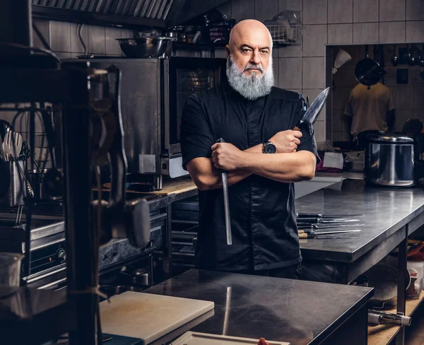 Grauhaariger Koch hält Küchengeräte in der Küche — Stockfoto