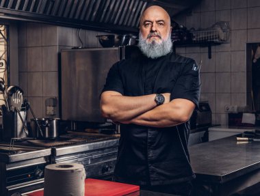 Mutfakta siyah giysili gri saçlı şef.