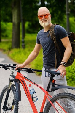 Doğanın parkında bisiklet süren yaşlı bir bisikletçi.