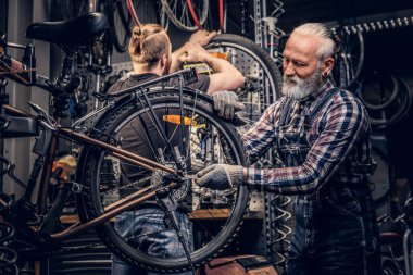 Yaşlı adam ve torunu tamirhanede birlikte bisiklet tamir ediyorlar.