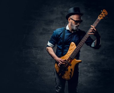 Havalı yaşlı hippi gitarist karanlık arka planda gitar çalıyor.