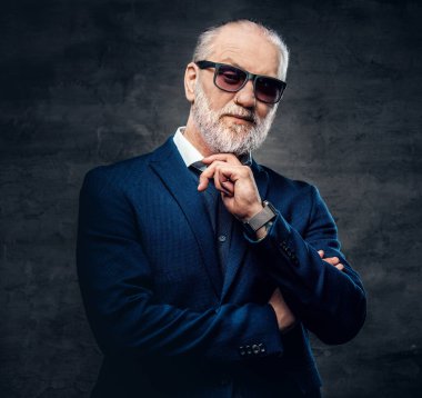 Koyu mavi ceketli, kendine güvenen ve şık yaşlı bir adam.