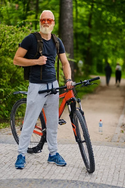 Biciclista idoso esportivo com bicicleta e mochila ao ar livre — Fotografia de Stock