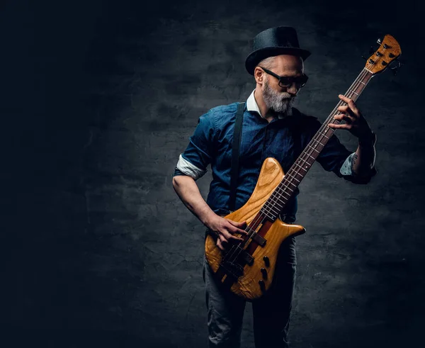 Cool anziano hipster chitarrista suonare la chitarra contro sfondo scuro — Foto Stock