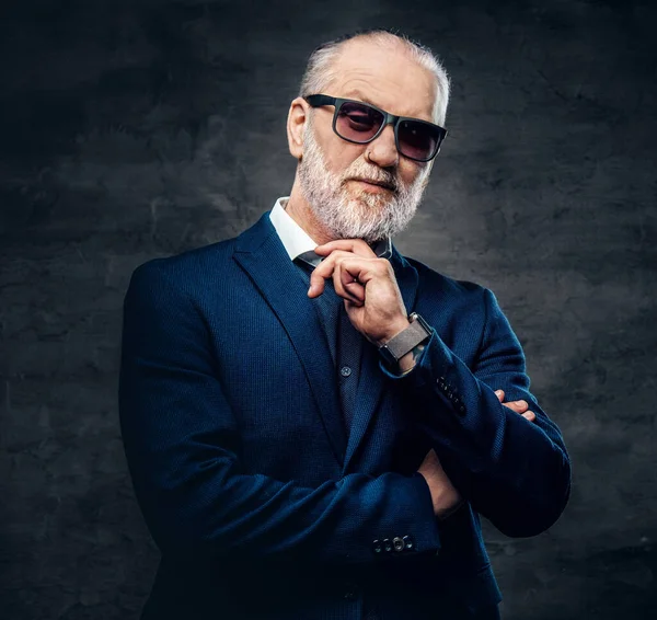 Koyu mavi ceketli, kendine güvenen ve şık yaşlı bir adam.