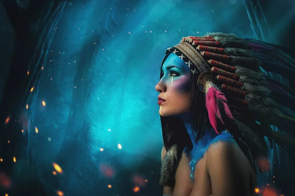 Волшебная женщина-вождь в перьевой головной убор против ночного леса — стоковое фото