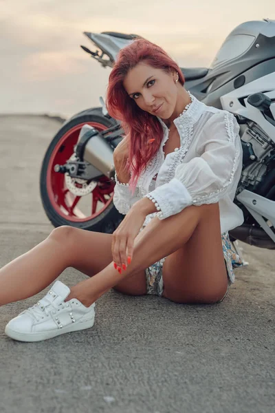 Fröhliche Radfahrerin posiert auf Straße rund um ihr Motorrad — Stockfoto