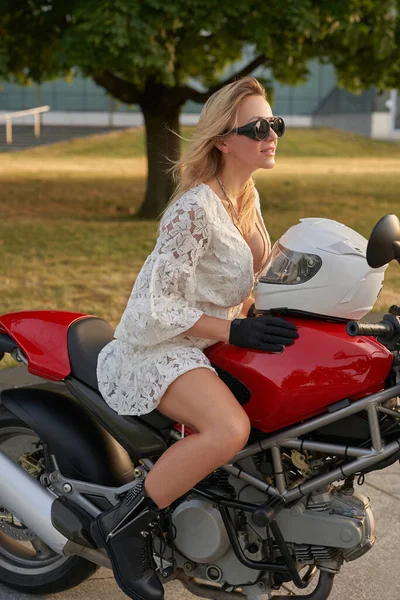 Kasklı ve motosikletli kadın motosikletçi gündüz vakti dışarıda