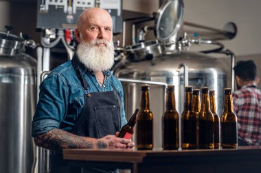 Bira üretim fabrikasında çalışan kel yaşlı bir adam.