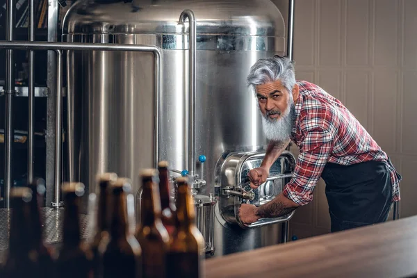 Önlük giymiş yaşlı adam modern bira fabrikasında çalışıyor. — Stok fotoğraf