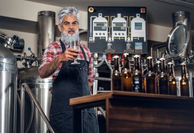 Bira fabrikasında poz veren eski bira üreticisi. Bira şişeleri var.