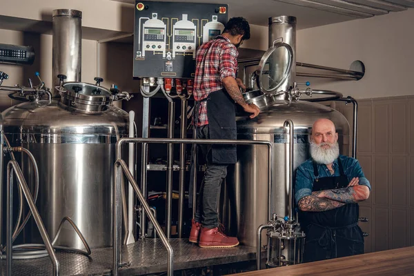 Un bătrân cu colegul său examinând butoaie uriașe cu bere — Fotografie, imagine de stoc