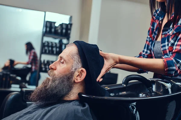 Woman barber washing hairs of bearded elderly hipster — 스톡 사진