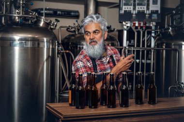 Modern bira fabrikasında kaliteli bira üreten yaşlı bir adam.