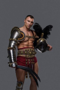 Gri arka planda kasklı yakışıklı gladyatör.