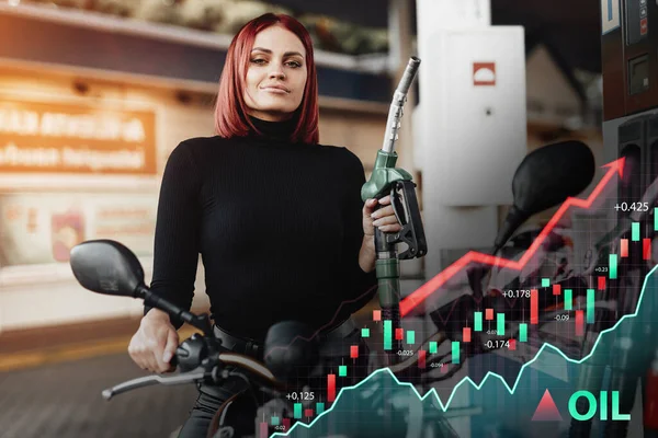 Motosikletli neşeli kadın benzin istasyonunda motorcusunu dolduruyor.