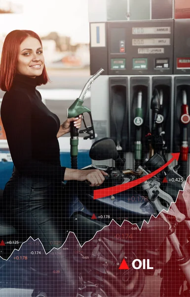 Mulher sorridente motociclista no posto de gasolina e aumento de preço — Fotografia de Stock