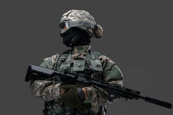 Храбрый солдат с винтовкой смотрит в сторону на сером фоне — стоковое фото