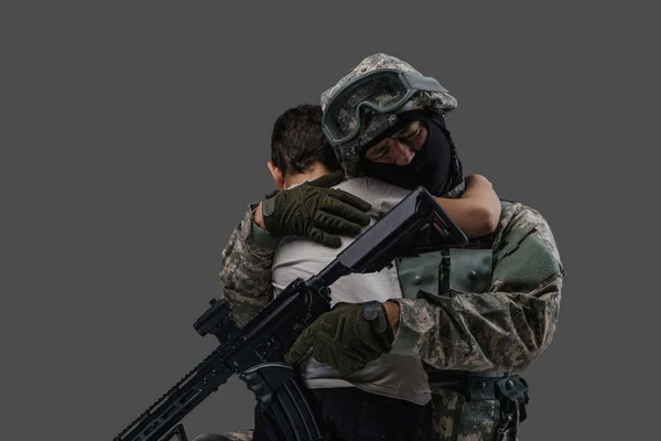 Στρατιώτης που αγκαλιάζει ένα μικρό παιδί απομονωμένο σε γκρι φόντο — Φωτογραφία Αρχείου