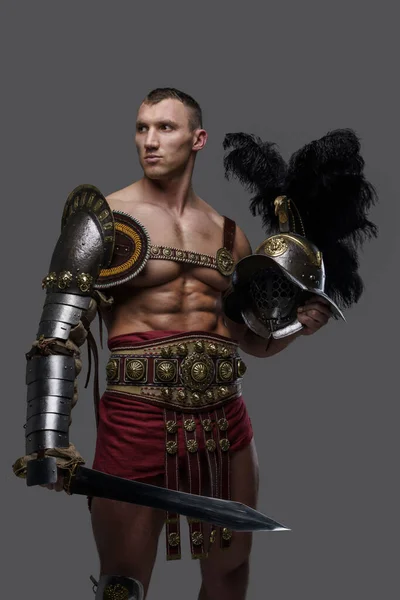 Glorious gladiator with gladius and helmet isolated on grey — Fotografia de Stock